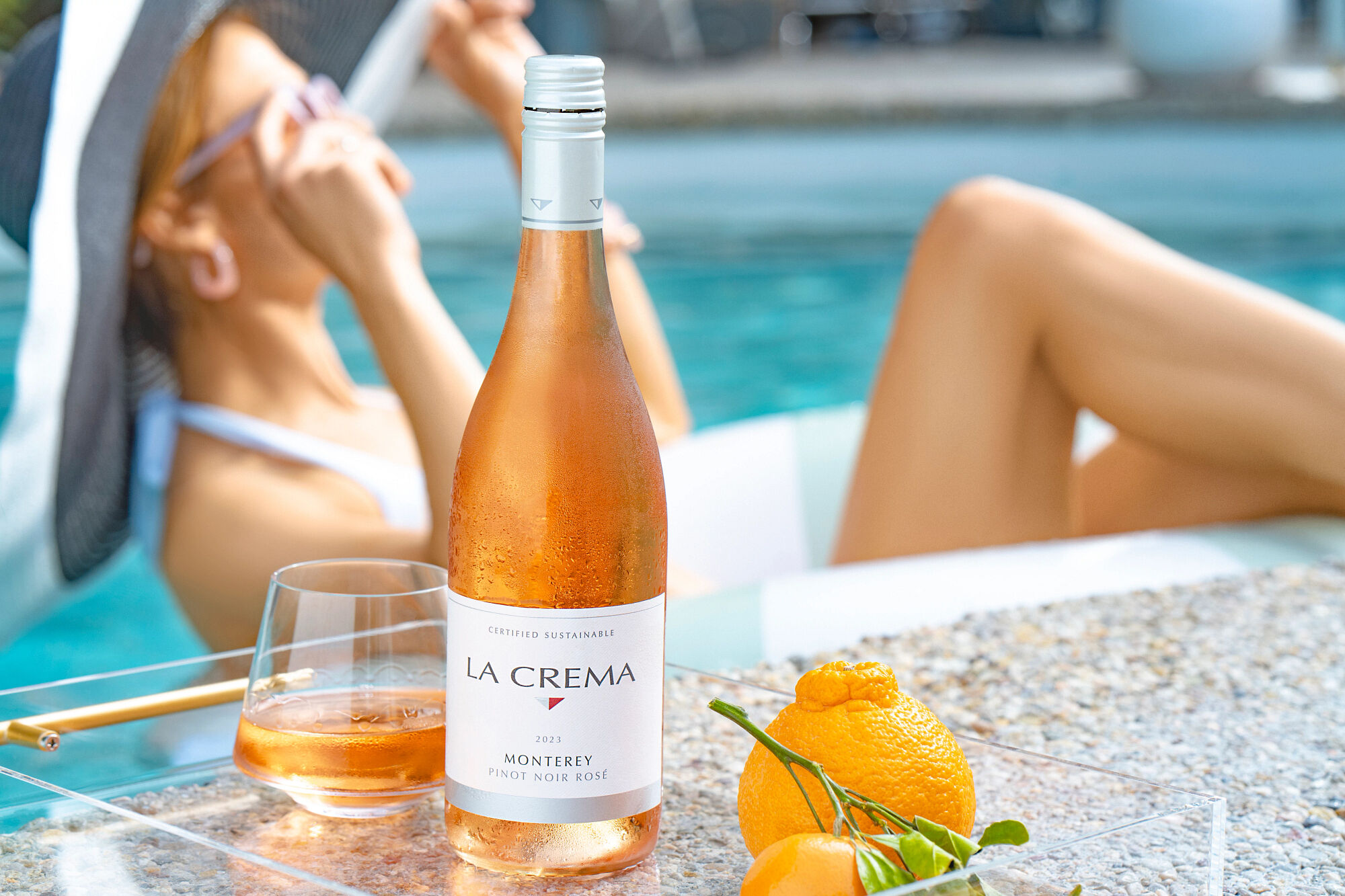 A women drinking La Crema Rosé by a pool